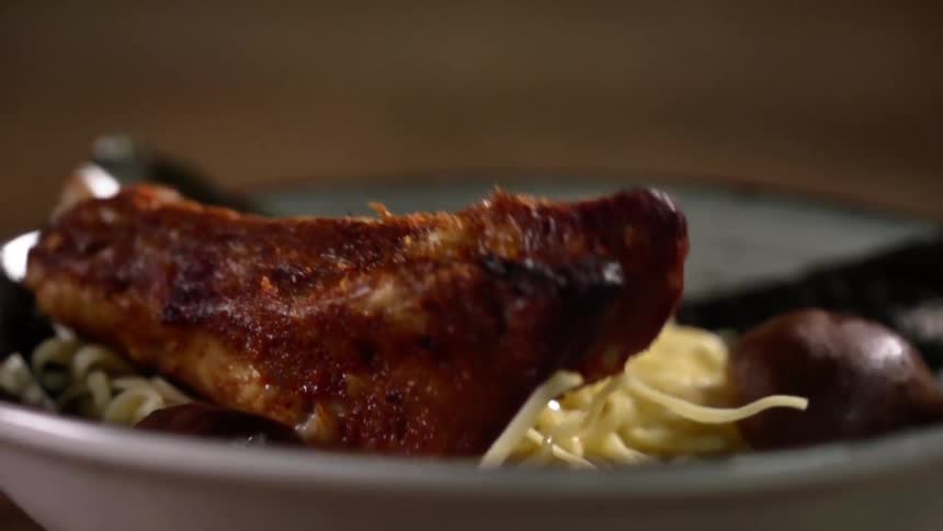 A rib falls in to a bowl with pasta in it