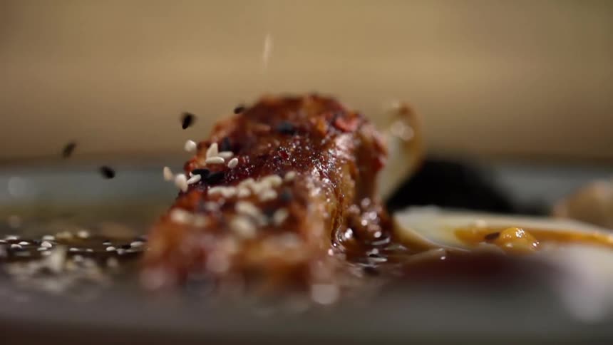 Black and white sesame seeds are dropped onto meat and broth as garnish