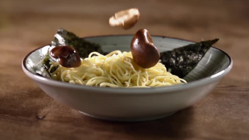 Mushrooms falling in to a bowl of pasta