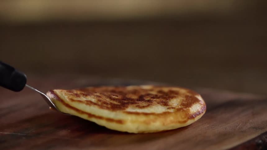 A pancake on a spatula is set on a wooden table