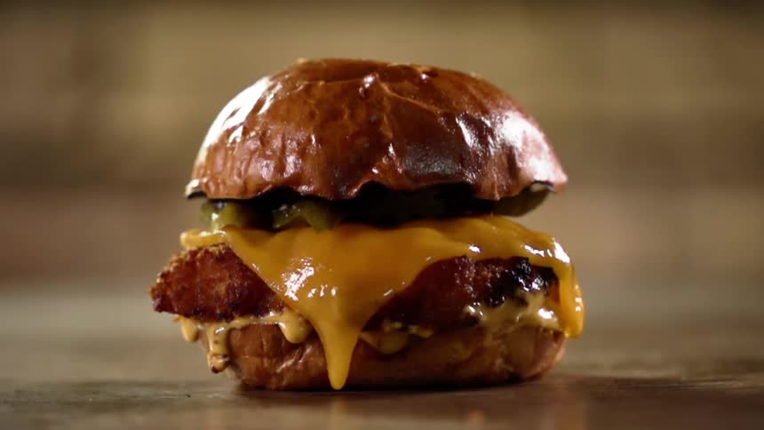 Burger bun falls over a cheese burger with pickles