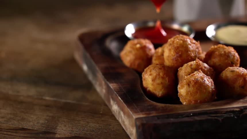 A man dips some fried food in ketchup