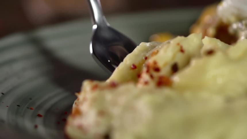 A fork slides into food and lifts a bite away from the plate