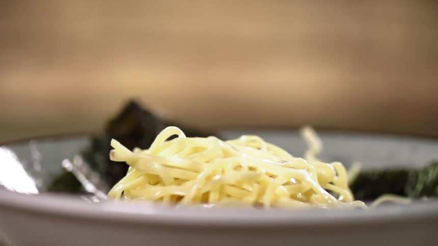 A clump of pasta falls into a bowl