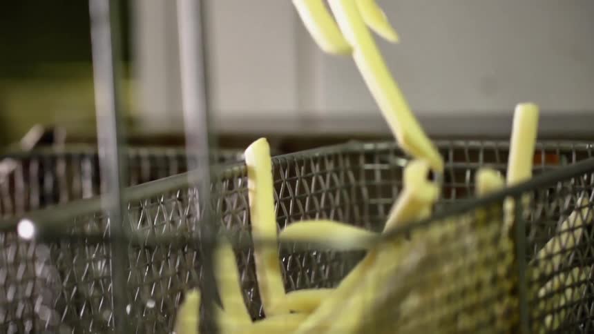 Fries in a bowl being placed in a basket