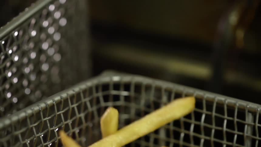 French fries bounce around in a metal fryer basket