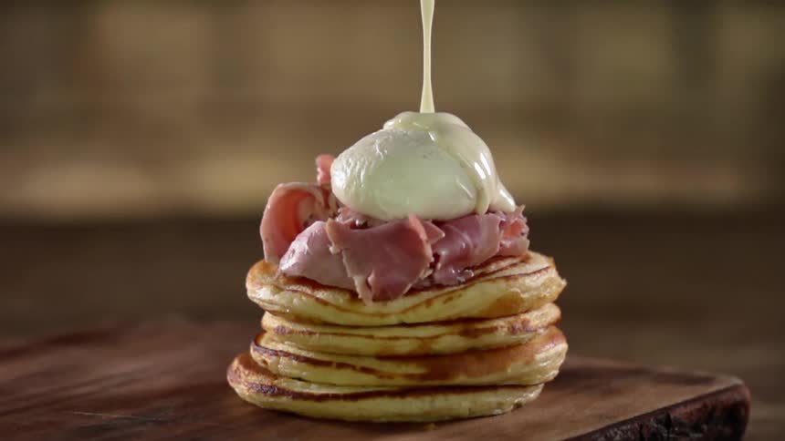 A cream sauce drizzles on top of a breakfast pancake creation