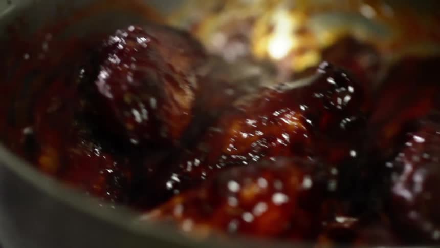 Wings covered in sauce are cooking in the pot