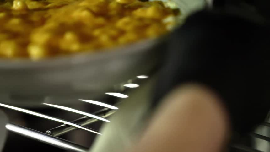 A person takes a dish of food off of a rack