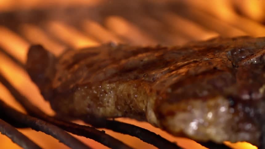Juicy steak is placed on the grill to cook over a fire
