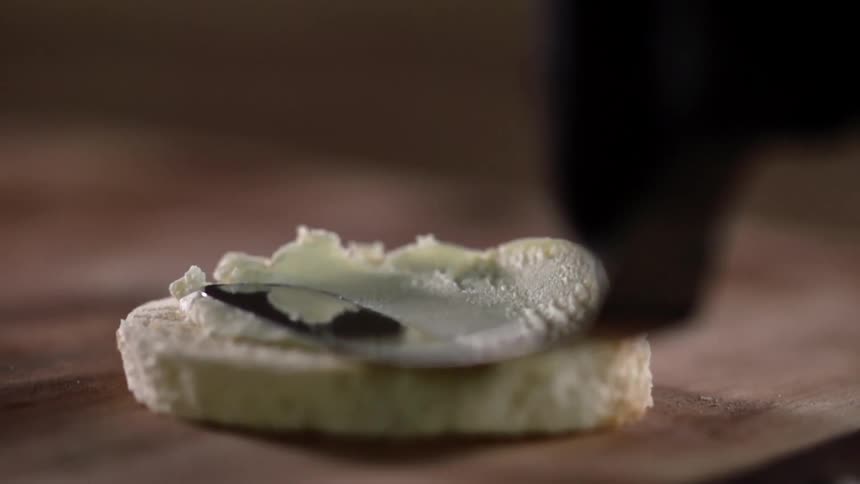 White cream cheese spread over a slice of bread with a spatula