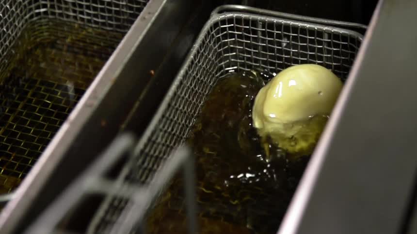 A ball of dough is dropped into a deep fryer
