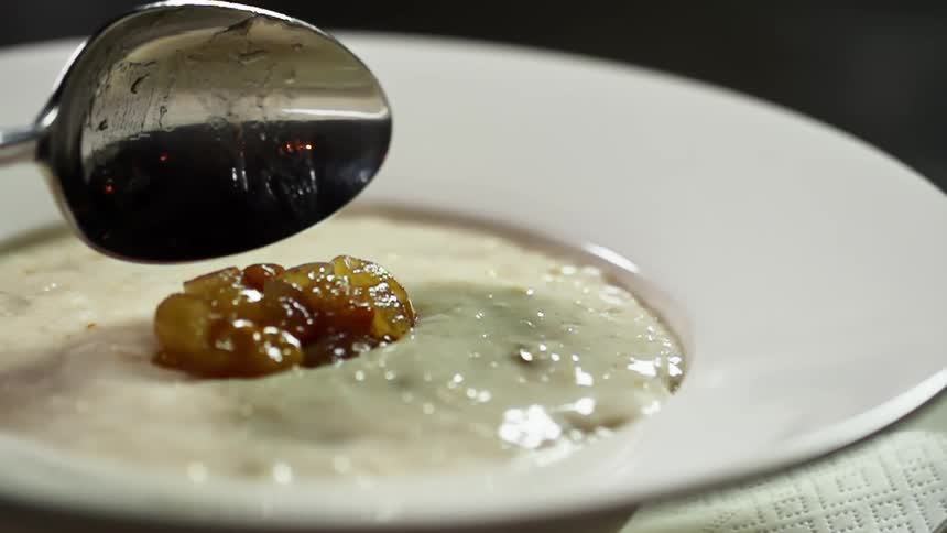 A spoon drops a piece of glazed meat into a bowl of soup