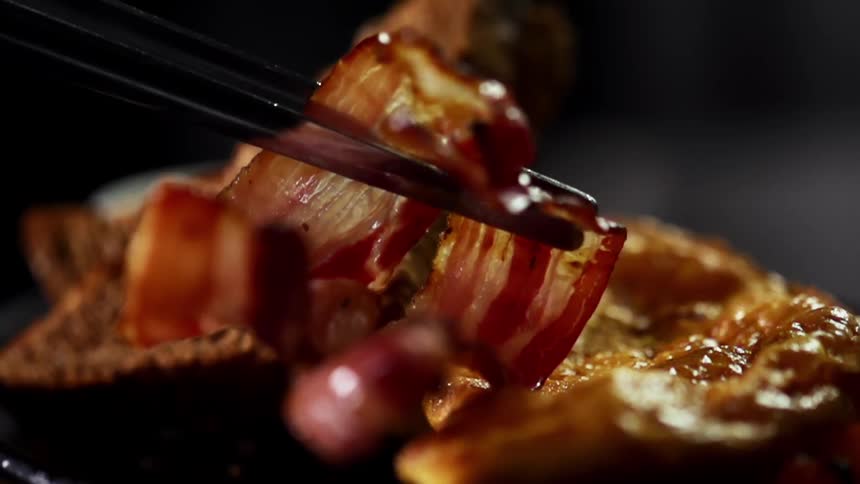 Bacon is set on a plate with toast and eggs
