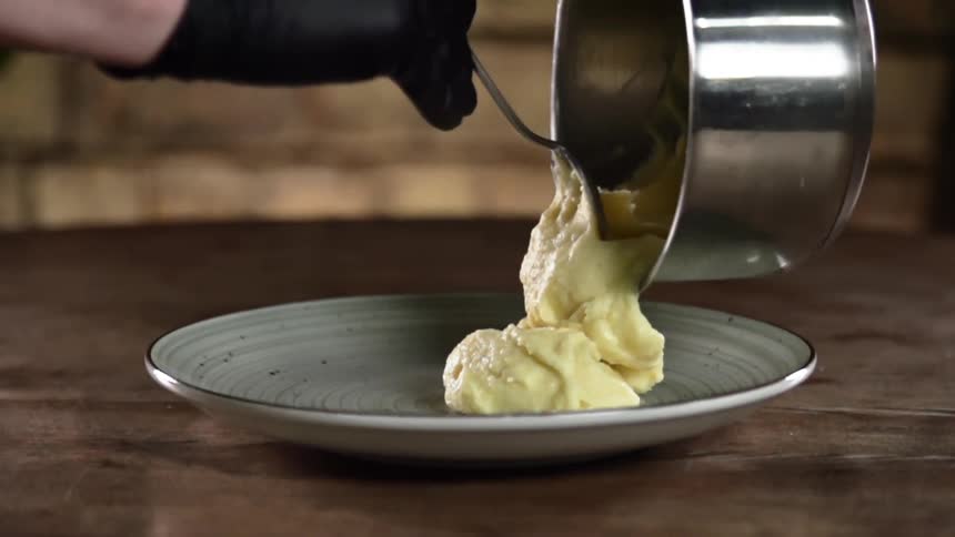 A person is scooping mashed potatoes onto the plate