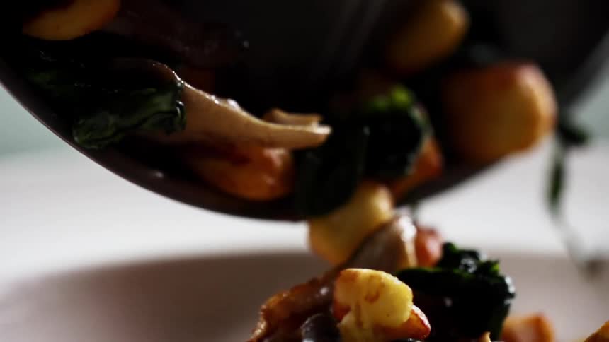 A bundle of vegetables pours into a white bowl
