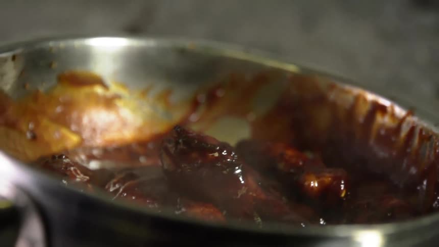 Chicken wings being tossed in sauce