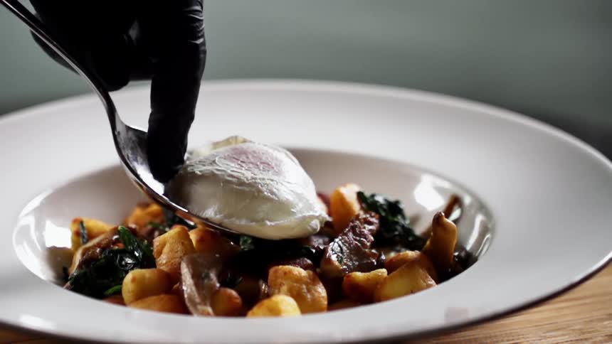 A person places an egg on a plate full of food