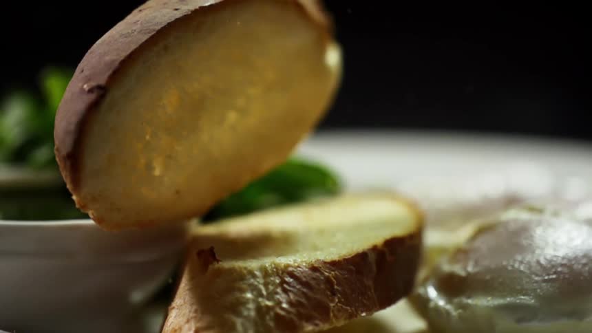 Sliced bread is dropped onto a plate next to a poached egg and greens