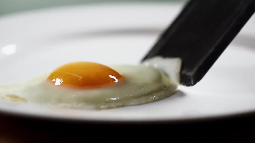 A spatula sets a sunny side up egg on a plate