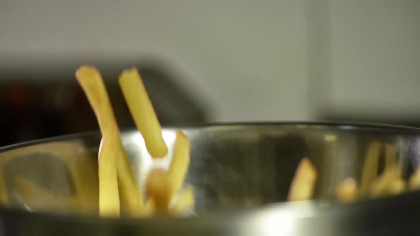 French fries are being dropped into an aluminum bowl