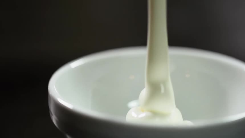 Cream being put in a bowl on a table