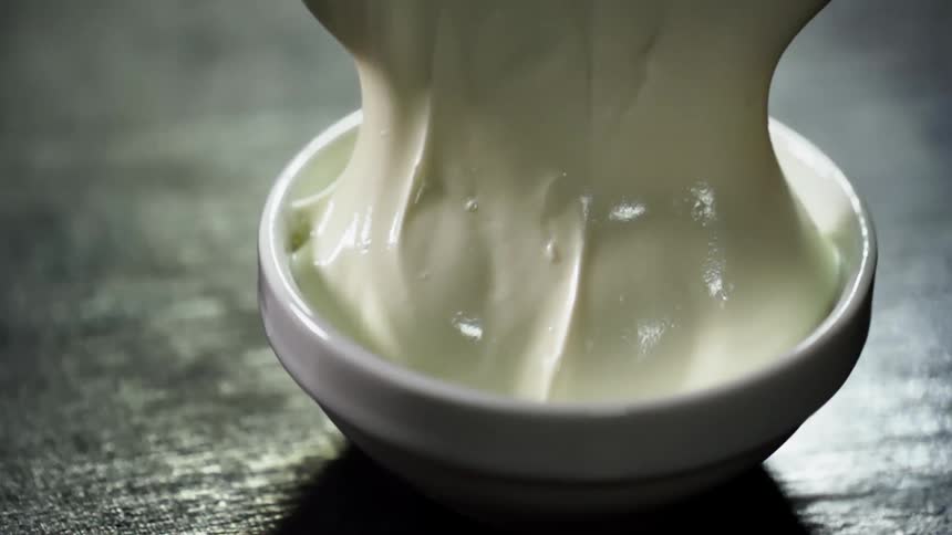 A spoon flips over a thick sauce in a small white bowl