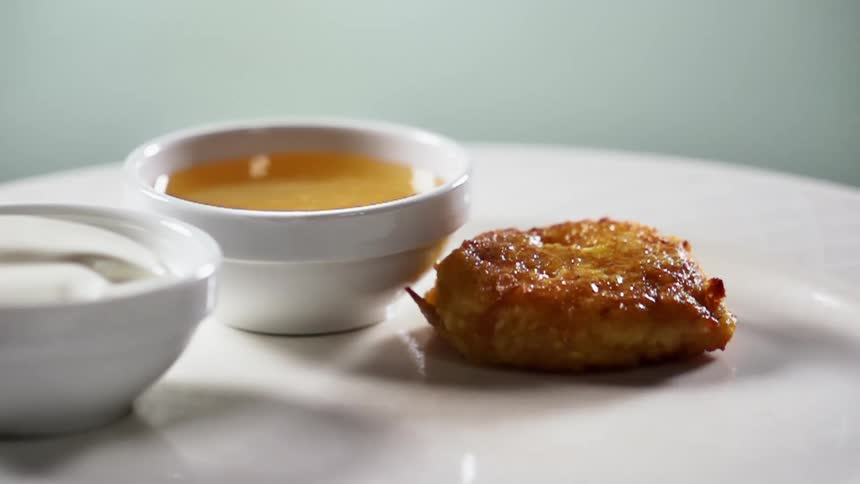 A gloved hands places cooked food on a white plate