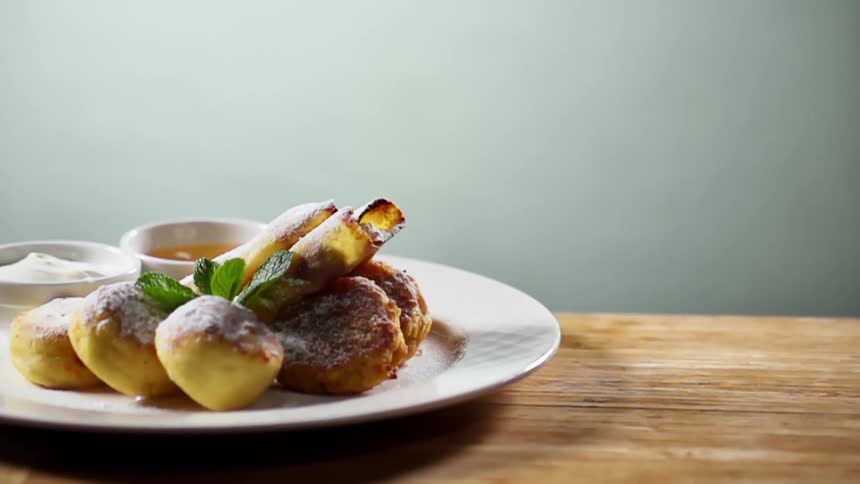 Mint cluster drops onto sugar coated pastries in white plate