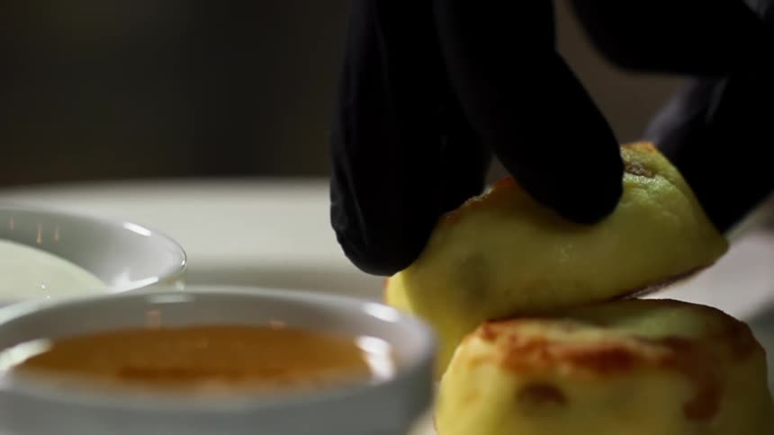A gloved hand places food onto a white plate