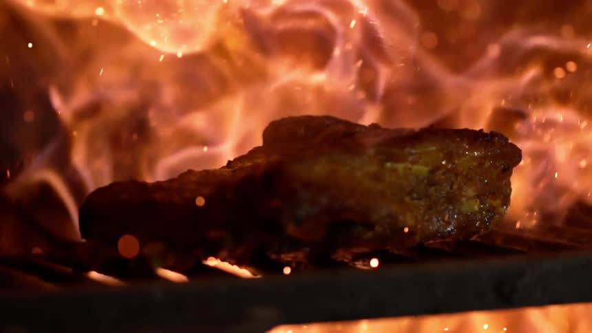 A piece of meat grilling over open flames