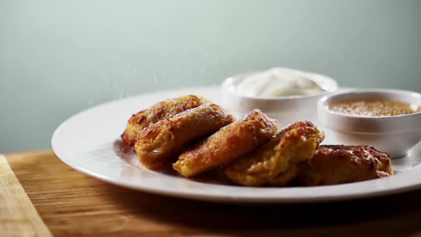 Powdered sugar is sprinkled over baked dessert on a white plate