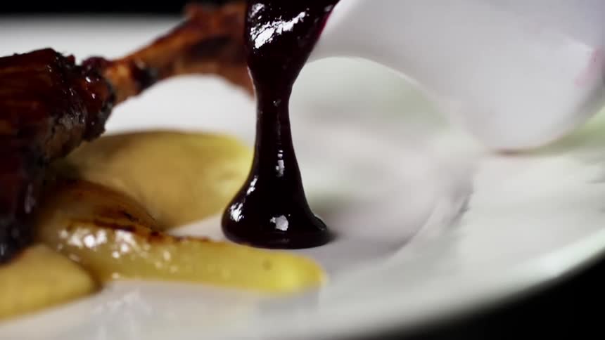 Barbecue sauce poured from a small pitcher onto a meal plate