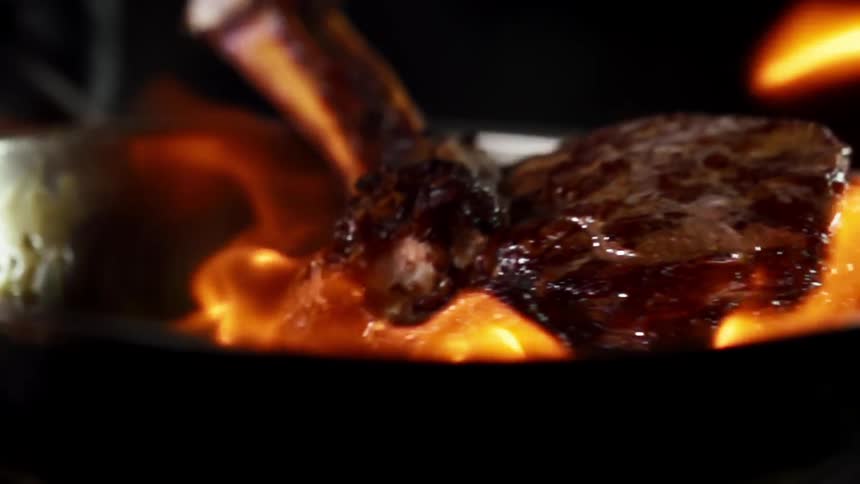 Lamb chop in a frying pan being flambeed