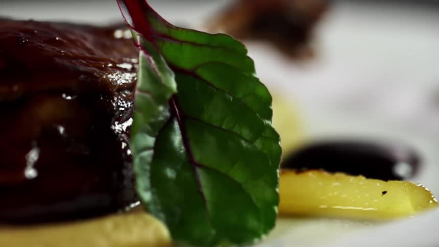 Vegetable leaf with maroon veins is added to meal on white plate