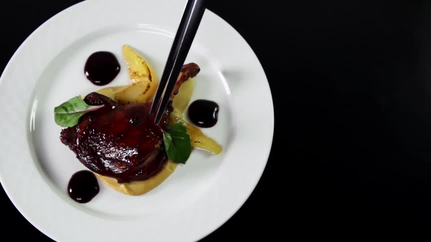 Chopsticks pick at a plate of food on a black surface