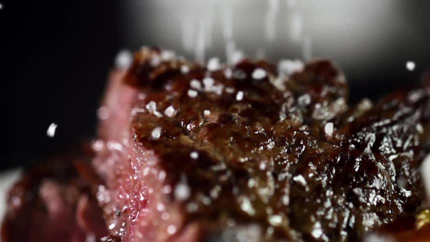 Salt crystal sprinkled on top of a browned sliced rare steak
