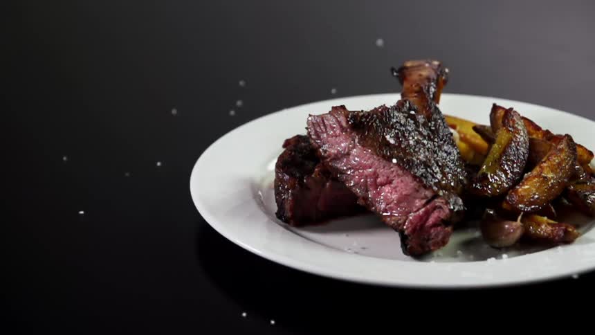 Salt falling on a plate with meat