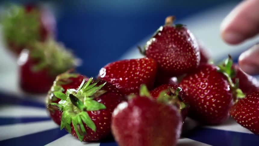 A handful of strawberries are tossed onto a blue and white swirl table