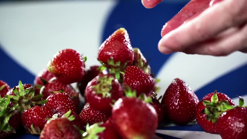 Person drops strawberries in a pile over a colorful surface