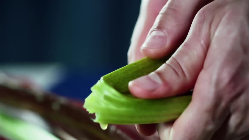 A white man snaps a green vegetable with his hands