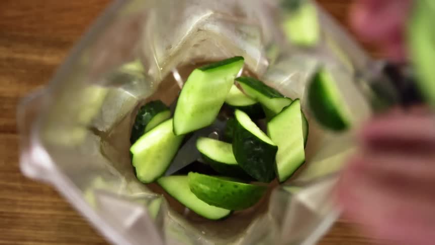 A person puts cucumbers in a blender