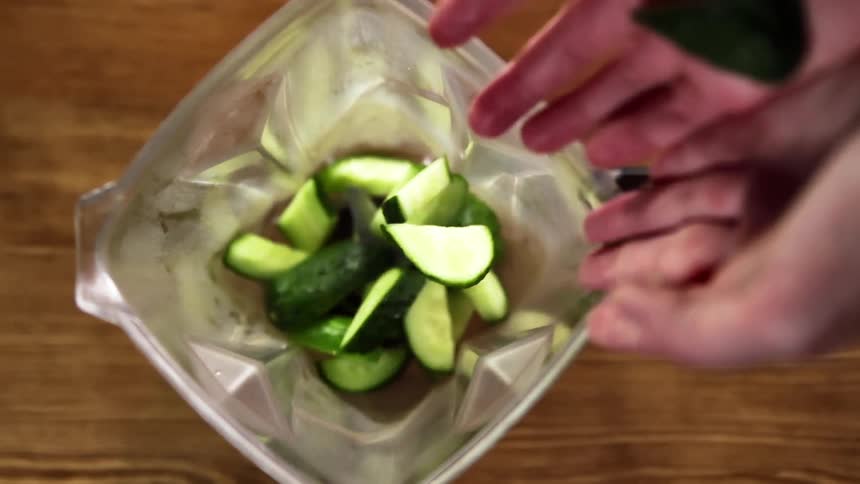 Chunks of cucumber are dropped into an empty blender