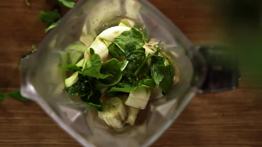Spinach is added to a blender with bananas