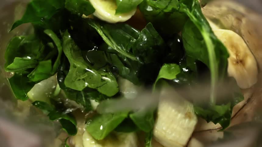 Liquid pouring over lettuce and banana slices in a glass bowl