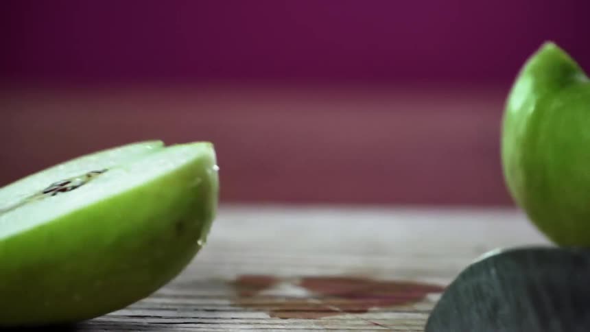 A man cuts a just washed green apple in half