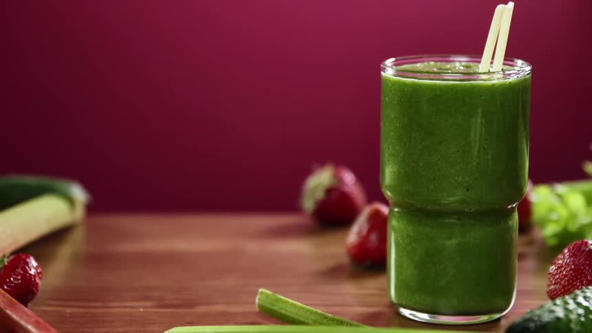 Two straws are put into a glass with a green smoothie