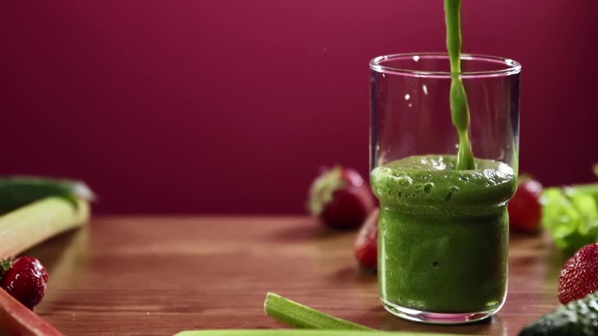 The glass is filled with a green smoothie