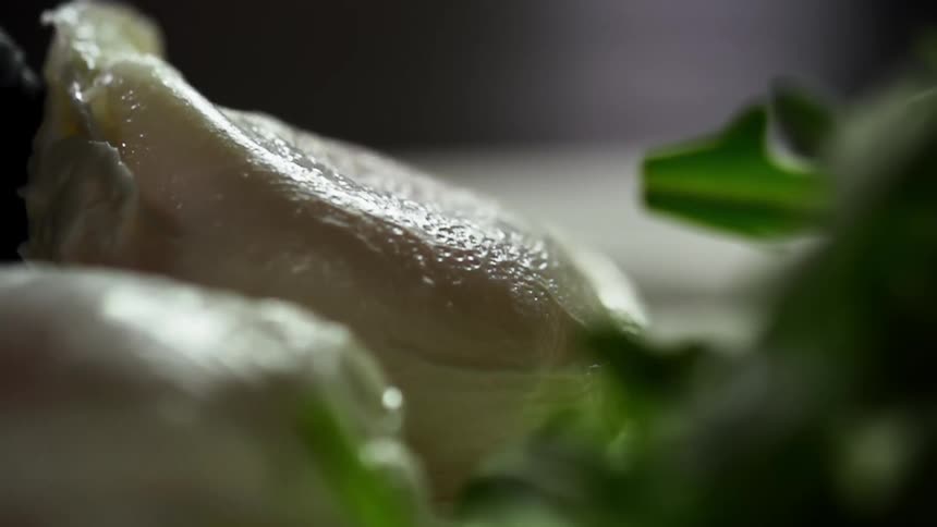 A hand in a black glove slides a piece of food onto a plate