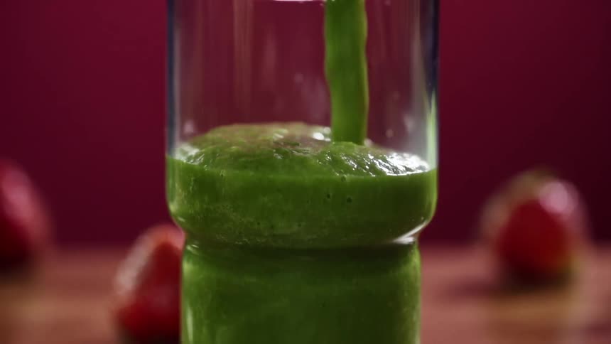 Green fluid pours out of a pitcher and fills a drinking glass